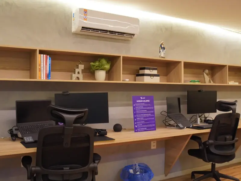 Estações de trabalho do escritório Wolf com cadeiras ergonômicas, monitores e placa Nossos Valores